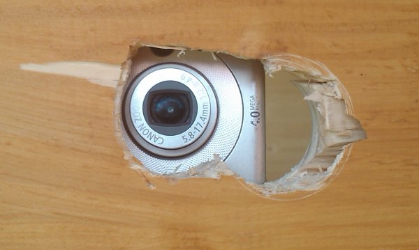 Camera lens from the outside looking through a hole in the wall