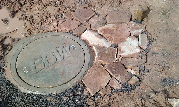 View of the cistern lid with the sand stone pavement next to it